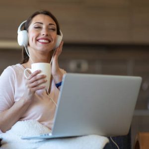 Beautiful young woman using laptop and listening to the music